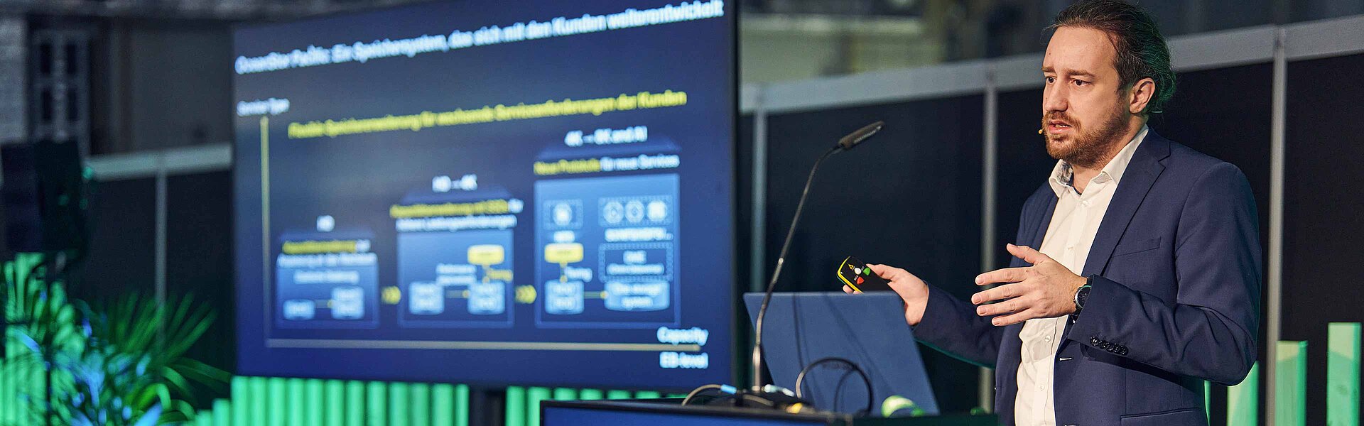 Speaker steht neben einem Bildschirm mit seiner Präsentation auf der Media Tec Stage.