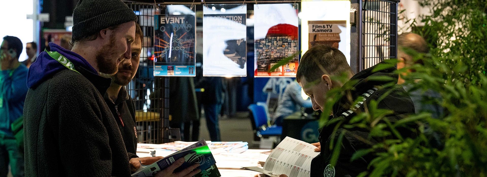 Three people are reading the magazines in the trade press area.