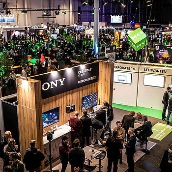 View of the HAMBURG OPEN hustle and bustle in Hall B6. Many people are chatting at the different stands or in the networking area.