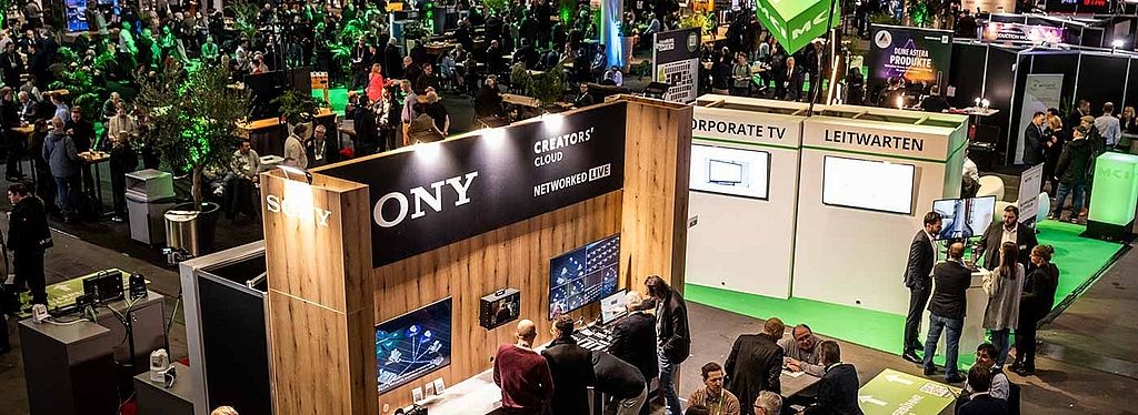 View of the HAMBURG OPEN hustle and bustle in Hall B6. Many people are chatting at the different stands or in the networking area.