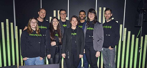 Team der HAMBURG OPEN. Acht Frauen und Männer lächeln in die Kamera. Vor ihnen steht ein Schild mit der Aufschrift: HAMBURG OPEN.