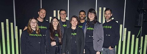 Team der HAMBURG OPEN. Acht Frauen und Männer lächeln in die Kamera. Vor ihnen steht ein Schild mit der Aufschrift: HAMBURG OPEN.