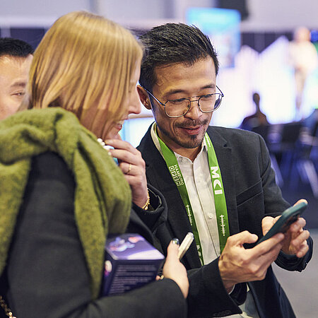 Besucher und Besucherin schauen gemeinsam auf ein Smartsheet und unterhalten sich.